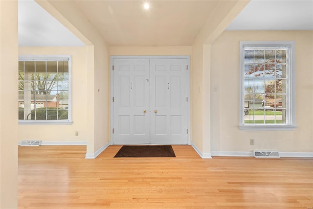 foyer entrance with visible vents, light wood-style flooring, baseboards, and a healthy amount of sunlight