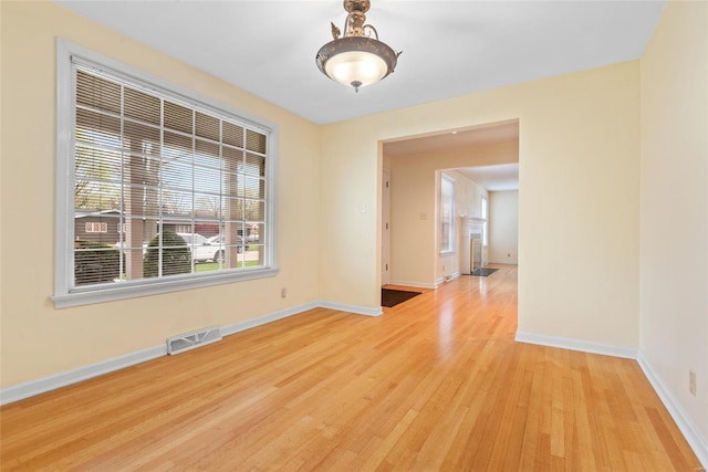 empty room featuring light wood-style flooring, baseboards, and visible vents