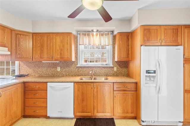 kitchen with white appliances, backsplash, brown cabinets, ceiling fan, and a sink