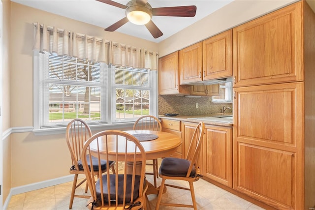 dining room with a healthy amount of sunlight, light tile patterned floors, baseboards, and a ceiling fan