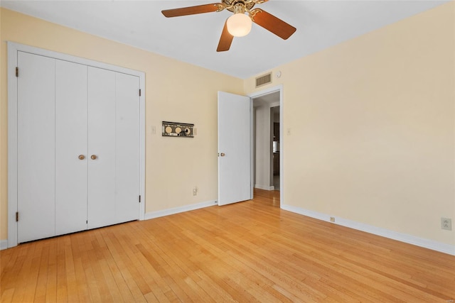 unfurnished bedroom featuring a closet, baseboards, visible vents, ceiling fan, and light wood-type flooring