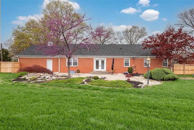 rear view of house with french doors, a lawn, fence, and brick siding