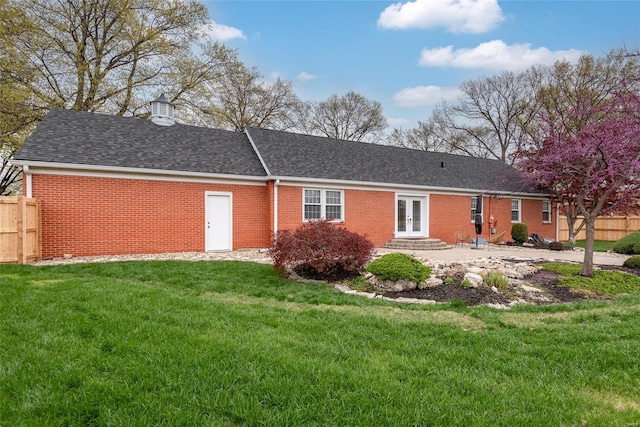 back of house featuring brick siding, french doors, fence, and a lawn