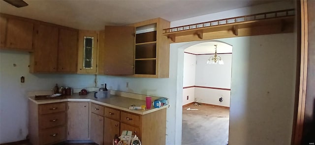 kitchen with light countertops, brown cabinetry, open shelves, and an inviting chandelier