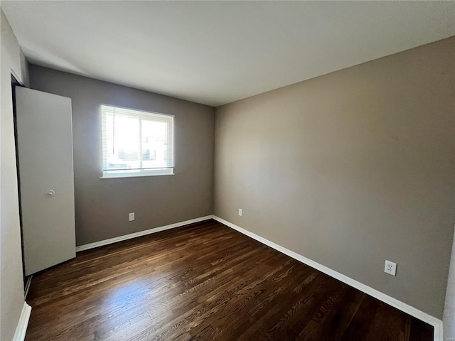 empty room with dark wood-style floors and baseboards