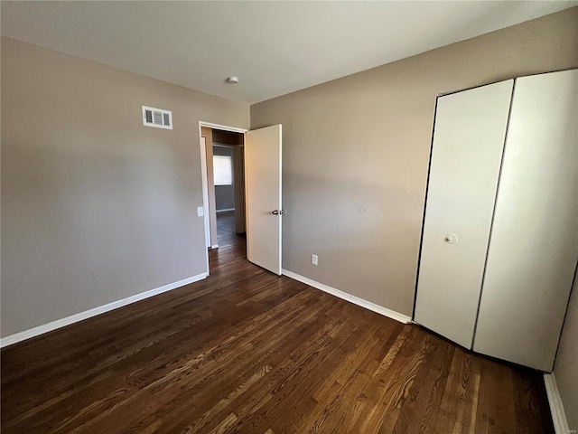 unfurnished bedroom with baseboards, visible vents, and dark wood-style flooring