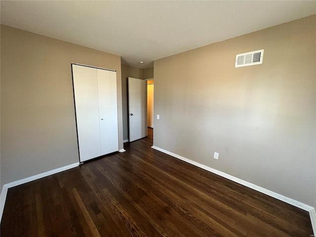 unfurnished bedroom with visible vents, baseboards, a closet, and dark wood-style flooring