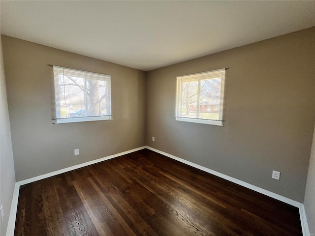 spare room with dark wood finished floors and baseboards