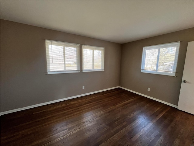 spare room featuring baseboards and dark wood-style flooring