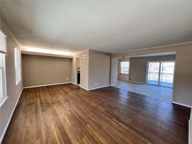 empty room featuring dark wood finished floors, baseboards, and visible vents