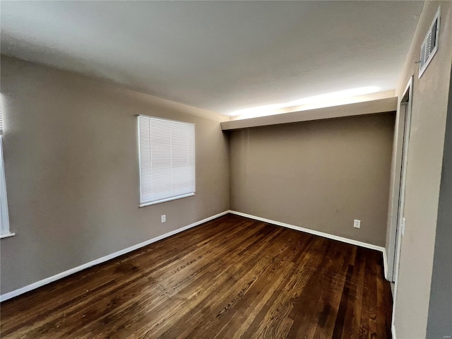 unfurnished bedroom featuring visible vents, baseboards, and dark wood-style flooring