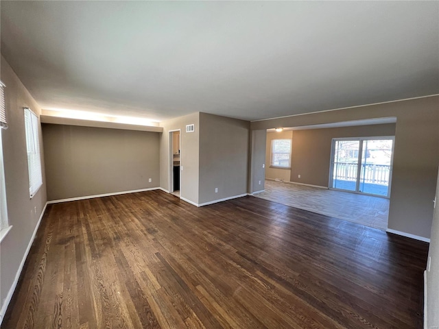 spare room featuring visible vents, baseboards, and dark wood-style flooring