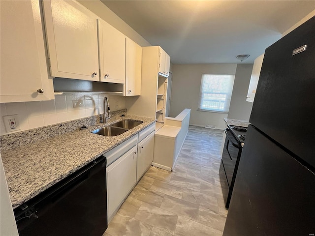 kitchen with light stone countertops, a sink, black appliances, white cabinetry, and backsplash