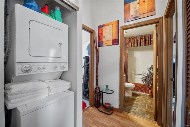 laundry room featuring stacked washer / dryer and wood finished floors