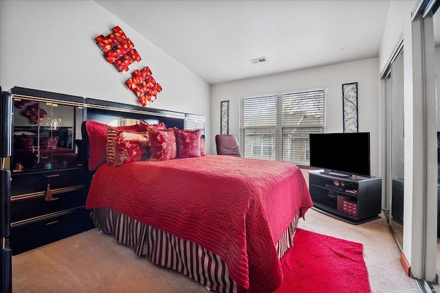 carpeted bedroom featuring a closet, lofted ceiling, and visible vents