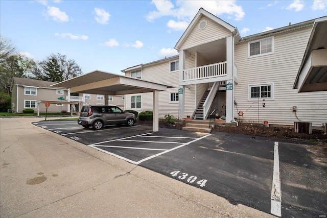 view of property featuring covered and uncovered parking and stairway