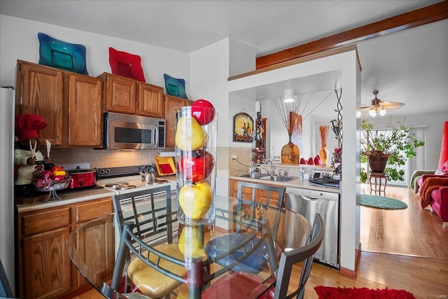 kitchen with a sink, brown cabinetry, appliances with stainless steel finishes, and decorative backsplash