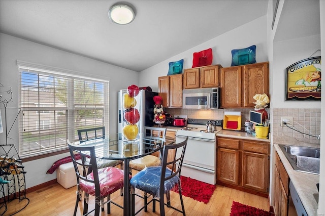 kitchen featuring white electric range oven, stainless steel microwave, a sink, and brown cabinets