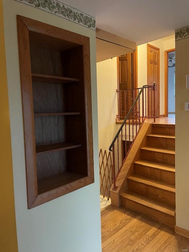 stairs with built in features and wood finished floors