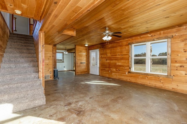 entryway with ceiling fan, concrete floors, visible vents, stairs, and wooden walls