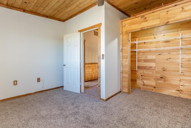 unfurnished bedroom with wood walls, carpet flooring, wood ceiling, and baseboards