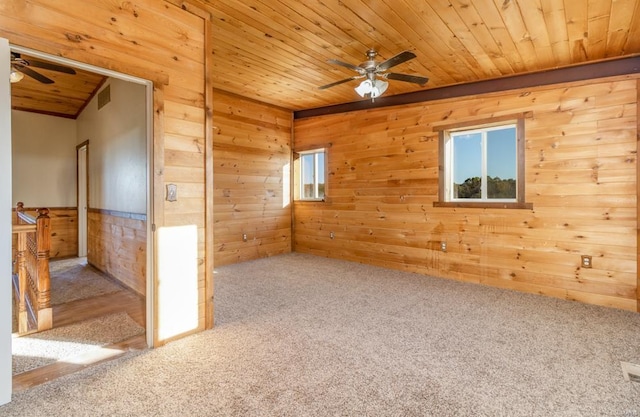carpeted empty room featuring wood walls, ceiling fan, visible vents, and wood ceiling