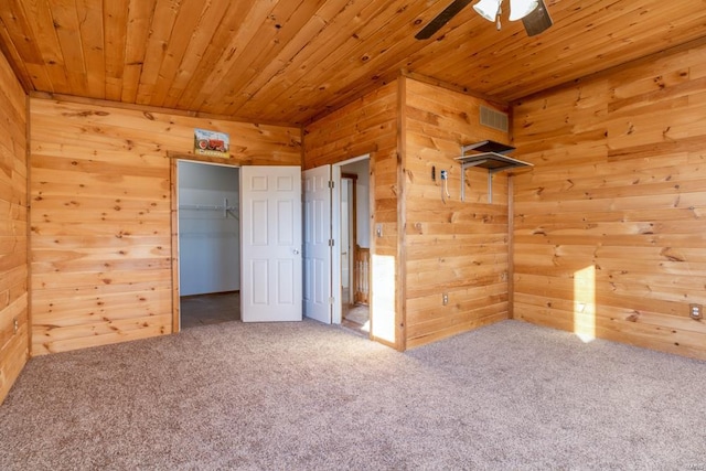 unfurnished bedroom featuring visible vents, wooden ceiling, carpet floors, and wood walls