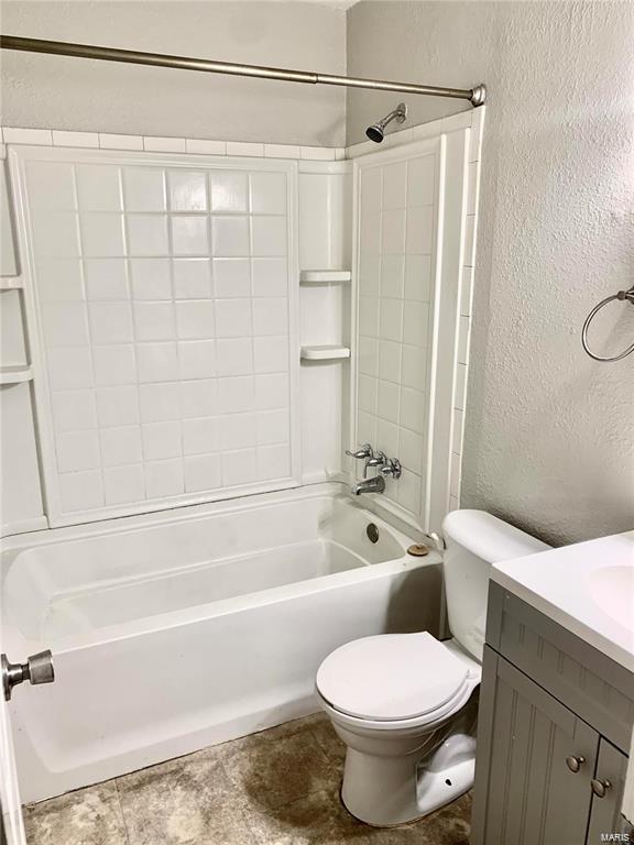 full bathroom featuring a textured wall, vanity,  shower combination, and toilet