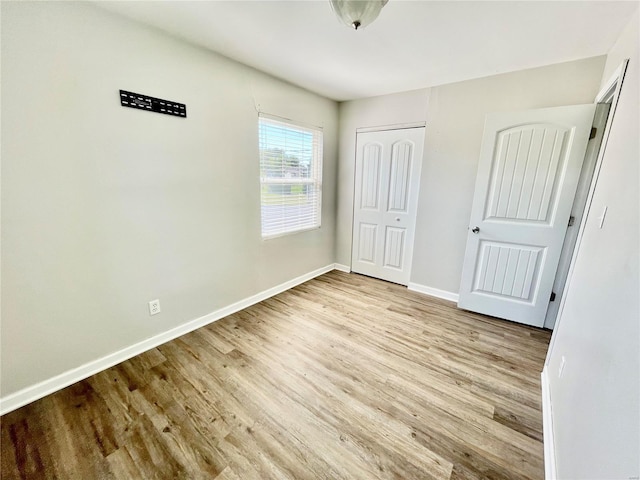 unfurnished bedroom with wood finished floors, a closet, and baseboards