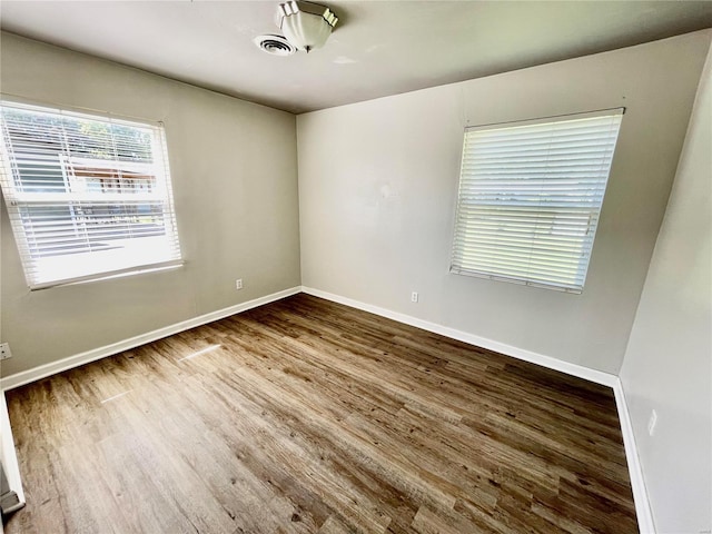 unfurnished room featuring visible vents, baseboards, and wood finished floors