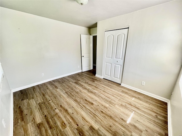 unfurnished bedroom with baseboards, wood finished floors, and a closet
