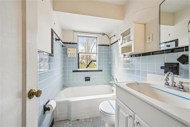 bathroom with toilet, tile walls, shower / bath combination, vanity, and tile patterned flooring