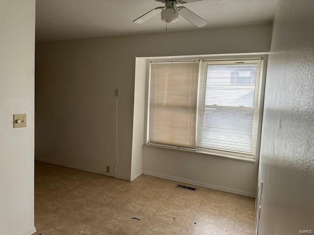 unfurnished room with visible vents, baseboards, ceiling fan, light floors, and a textured ceiling