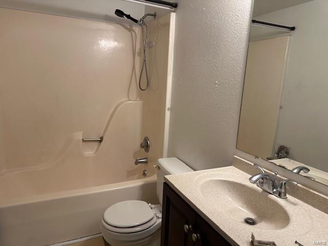 bathroom with toilet, vanity,  shower combination, and a textured wall