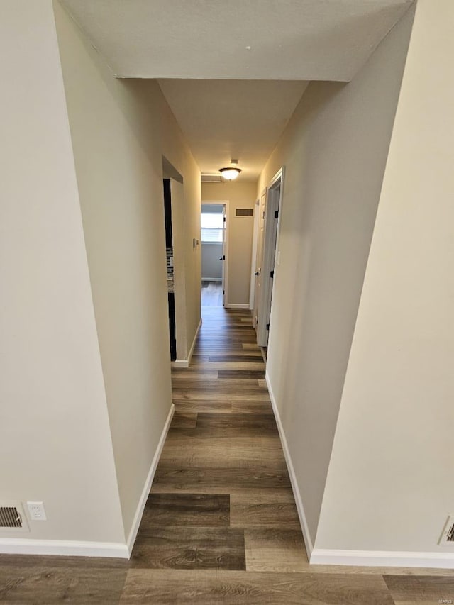 corridor featuring wood finished floors, visible vents, and baseboards