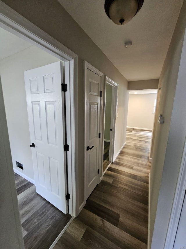 corridor with dark wood finished floors and baseboards