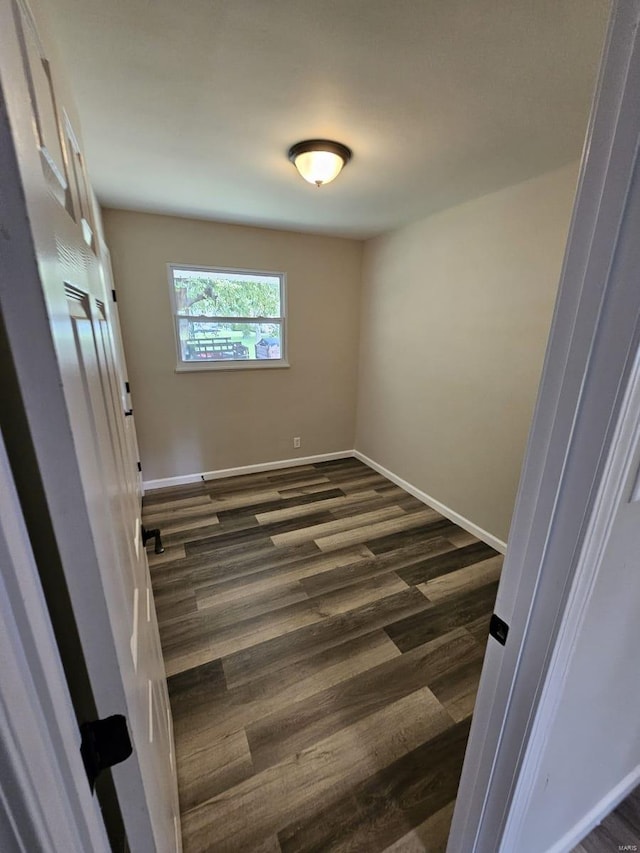 unfurnished bedroom with baseboards and dark wood-style flooring