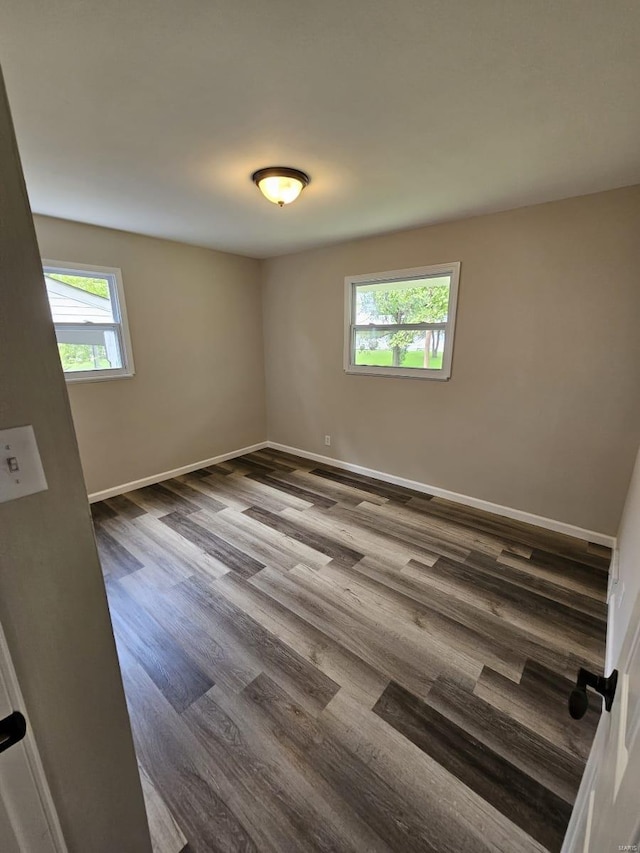 empty room featuring baseboards and dark wood-style flooring