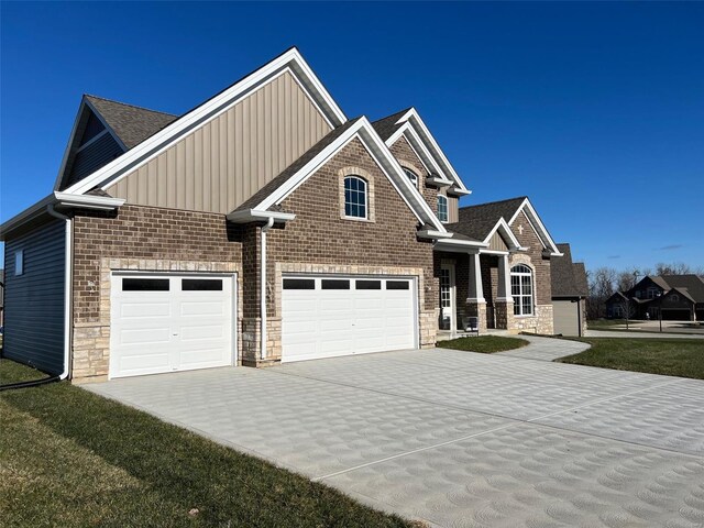 craftsman-style home with roof with shingles, stone siding, a garage, board and batten siding, and driveway