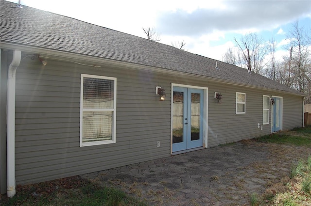 rear view of property featuring a patio area, french doors, and roof with shingles