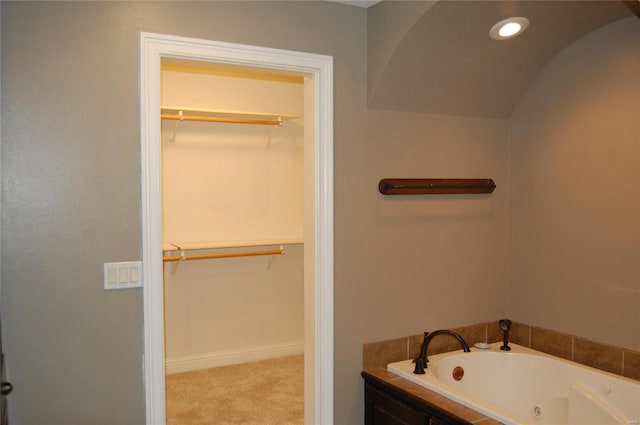 bathroom featuring recessed lighting, baseboards, a spacious closet, and a whirlpool tub