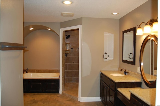 bathroom featuring a garden tub, a tile shower, recessed lighting, baseboards, and vanity