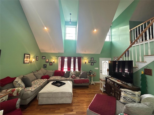 living room with baseboards, stairs, a towering ceiling, and wood finished floors