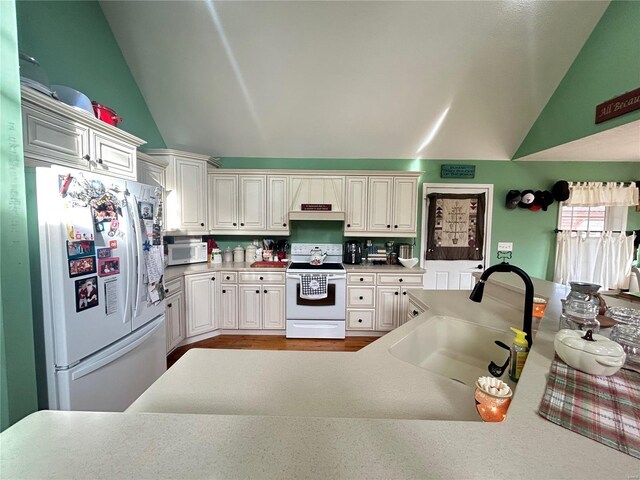 kitchen with white appliances, light countertops, lofted ceiling, and a sink