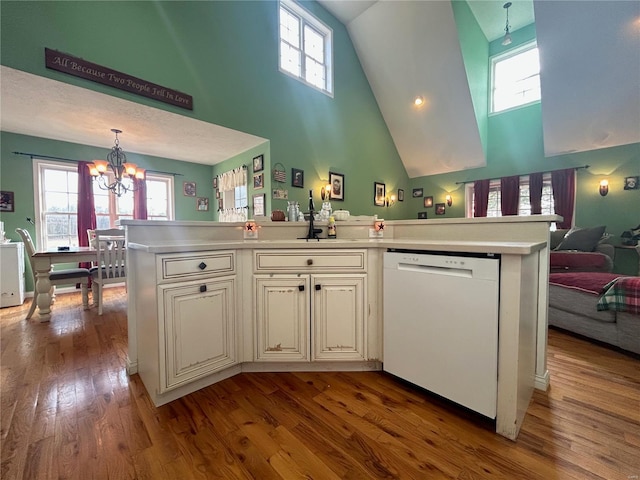 kitchen with wood finished floors, light countertops, dishwasher, a notable chandelier, and open floor plan