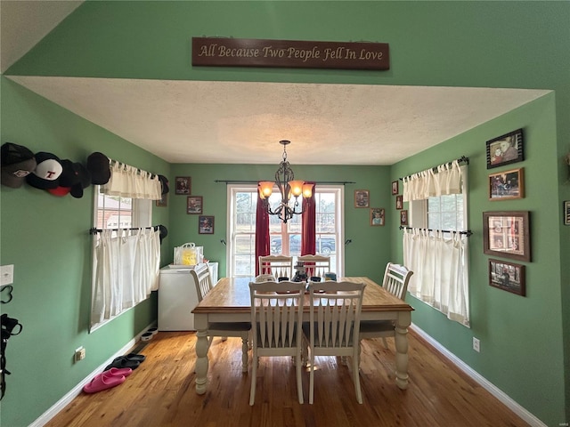 dining space featuring an inviting chandelier, plenty of natural light, and wood finished floors