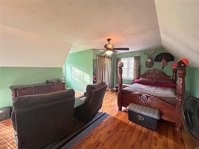 bedroom featuring lofted ceiling, a textured ceiling, wood finished floors, and a ceiling fan