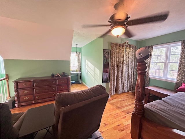 bedroom featuring multiple windows, a textured ceiling, a ceiling fan, and wood finished floors