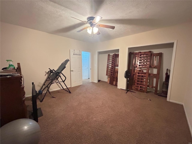 workout room with baseboards, a textured ceiling, ceiling fan, and carpet floors