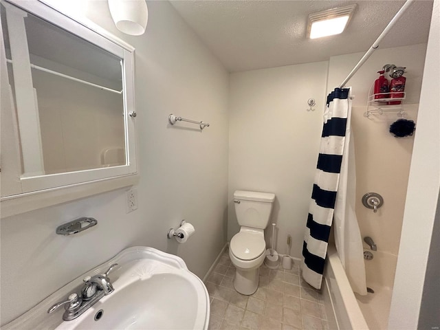 full bathroom featuring baseboards, toilet, shower / bath combo with shower curtain, a textured ceiling, and a sink